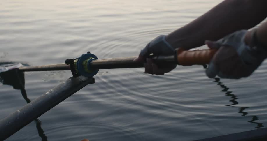 Woman places an oar on a stand in the rowboat on a lake at morning