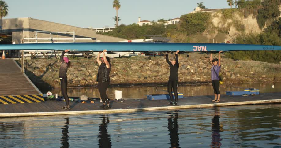 Four women work together to lift a kayak over their heads