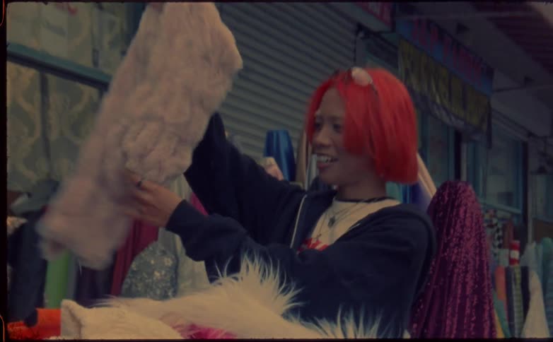 A teenage girl tries on a scarf at a shop on the street