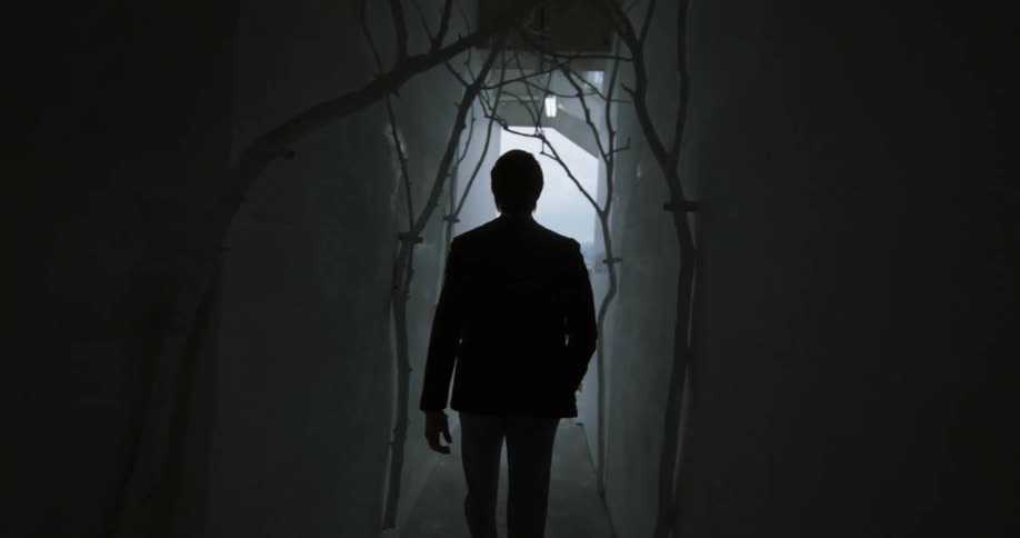 A man walks down the hall towards outside