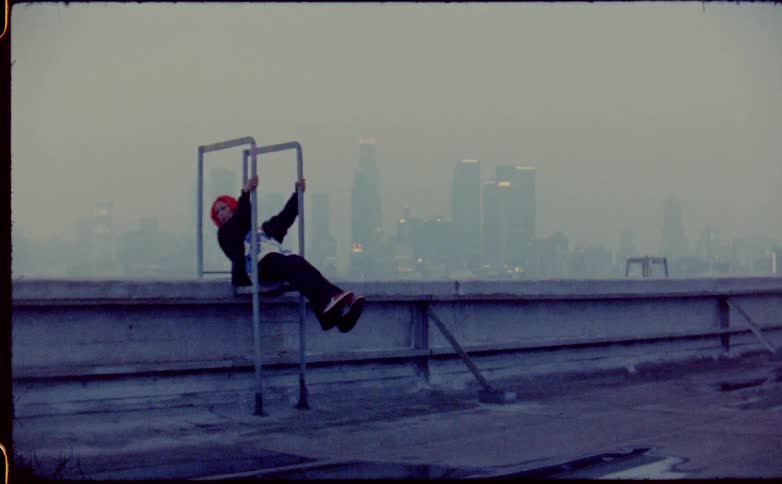 Young woman balancing on a stair on a roof in front of the city skyline