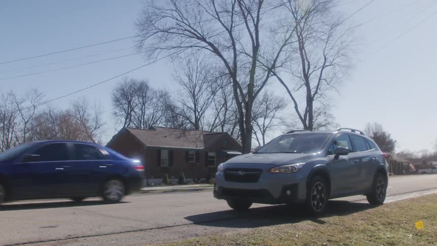 Car pulling up on side of the road and parking in a neighborhood in a small town