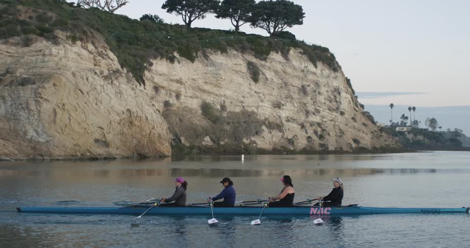 Four women rowing a boat in the water