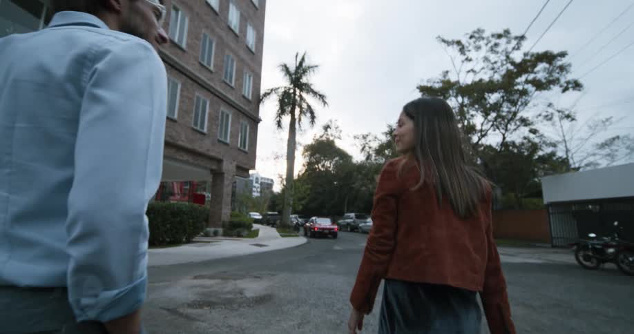A man and woman walk in the lot in front of the building