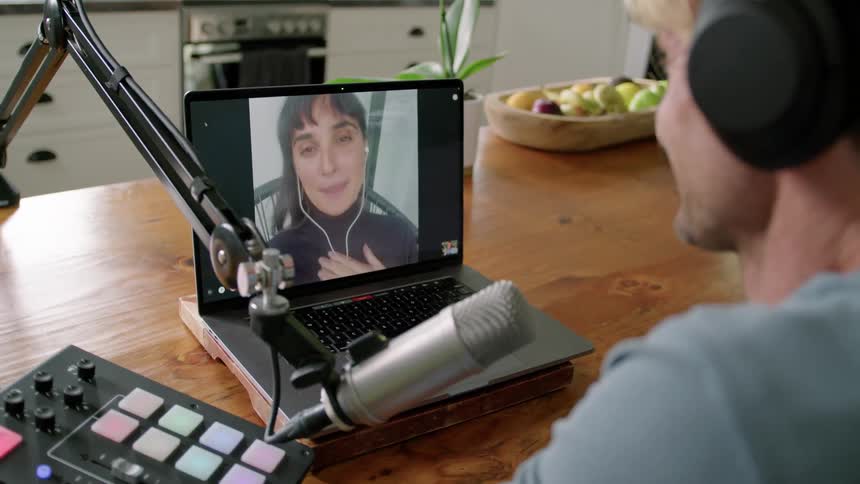 A man sits in his kitchen and video chats with a woman on a laptop