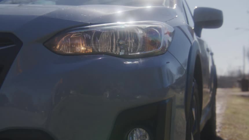 A white automobile is traveling slowly on a neighborhood street and it stops on the side of the road