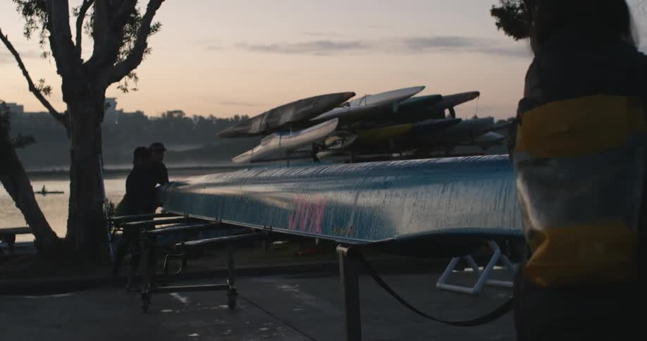 Two women flip a row boat on the rack