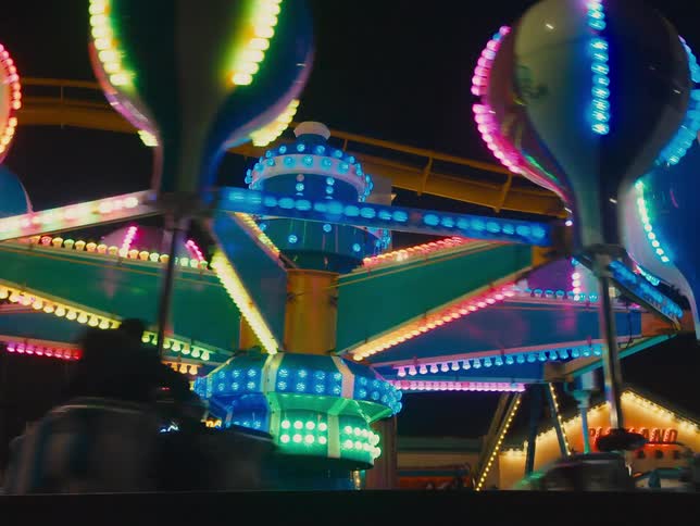 An amusement park ride is lit up and turning on a dark night