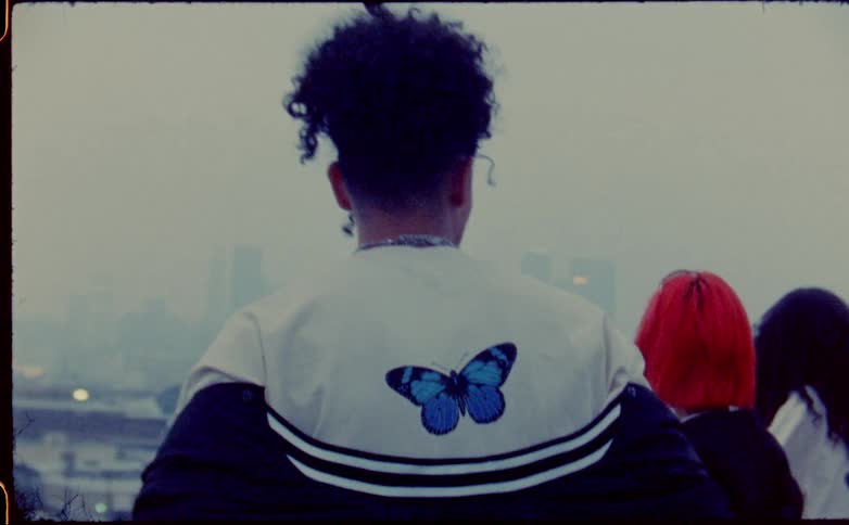 Group of friends standing on the roof of a building looking a the city skyline behind the fog