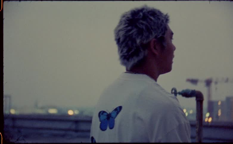 Young asian man walking on the roof of a building next to the city skyline at evening