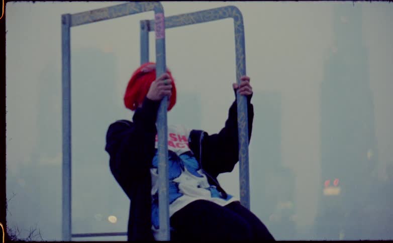 Woman with dyed red hair holds on to exercise bars and leans back then pulls herself forward on a foggy day