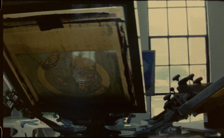 Young man opens the window in front of a turning screen printing machine