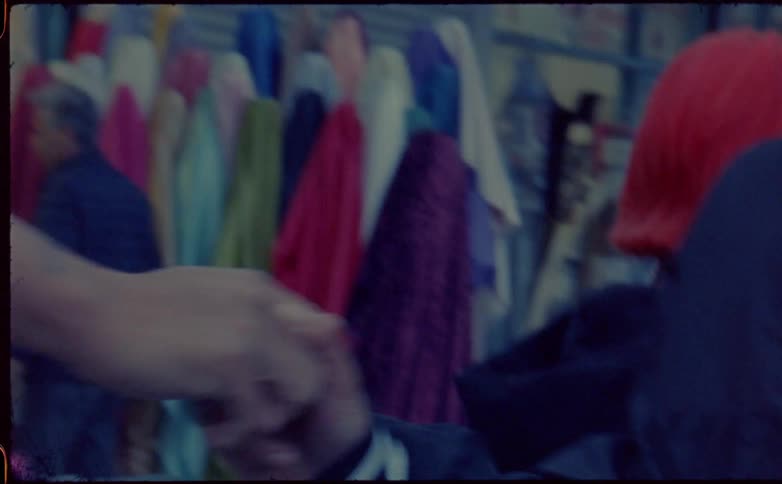 Two teenagers at a material shop shake hands and laugh