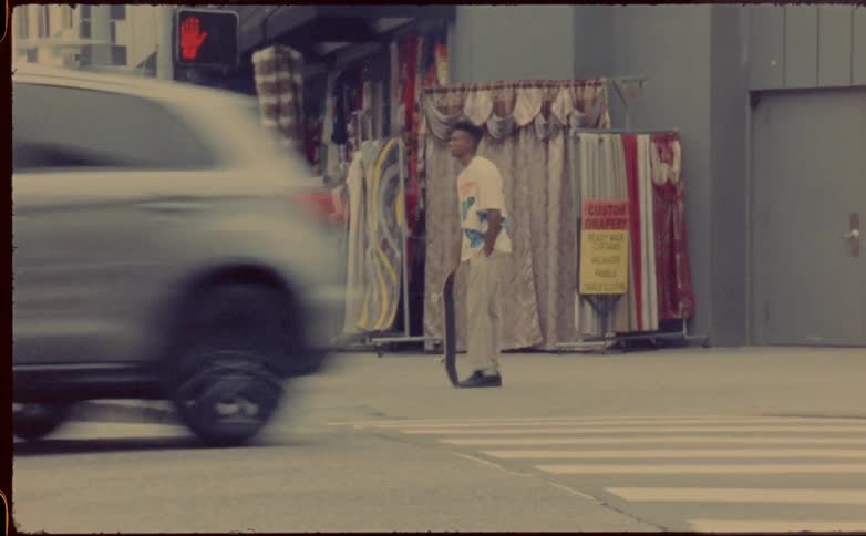 Speed up footage of a young man with a skateboard standing on a corner in the city
