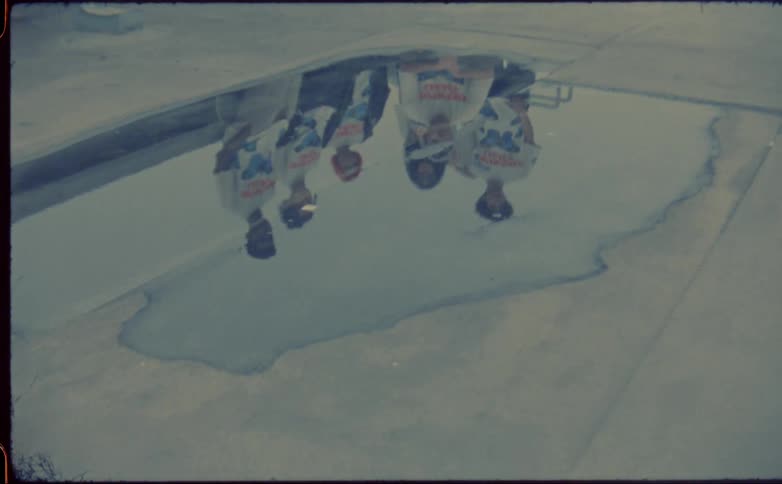 Reflection of a group of friends on a small pool of water on the roof of a building