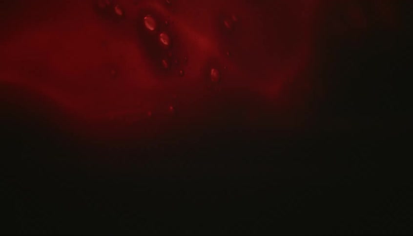 Air bubbles float in a viscous dark red liquid