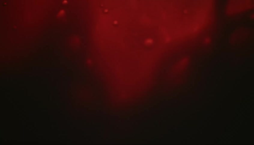 A light flashes as a red liquid swirls and bubbles