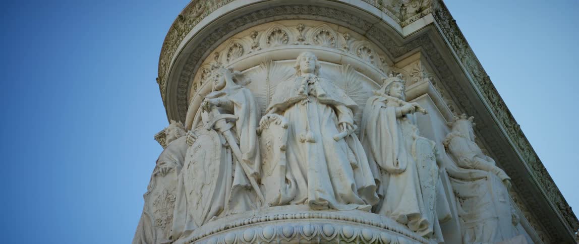 Sculptures of historical figures are carved onto the tower of a building
