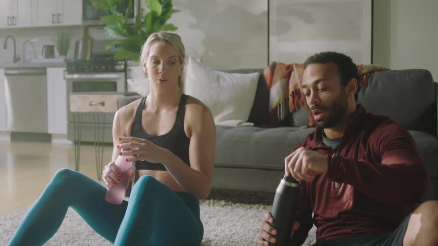 A man and woman drinking water after working out