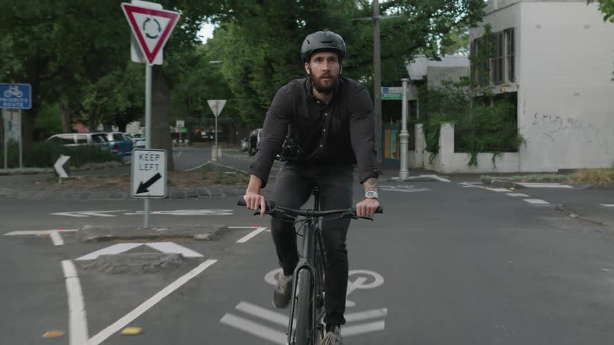 Cyclist rides bike along town street past parked vehicles