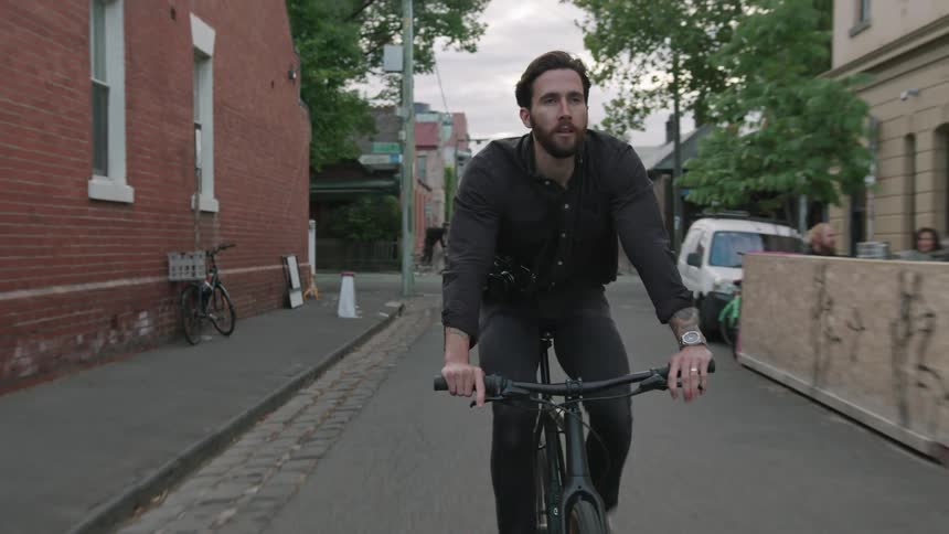 A man rides his bicycle down the center of neighborhood streets in a city
