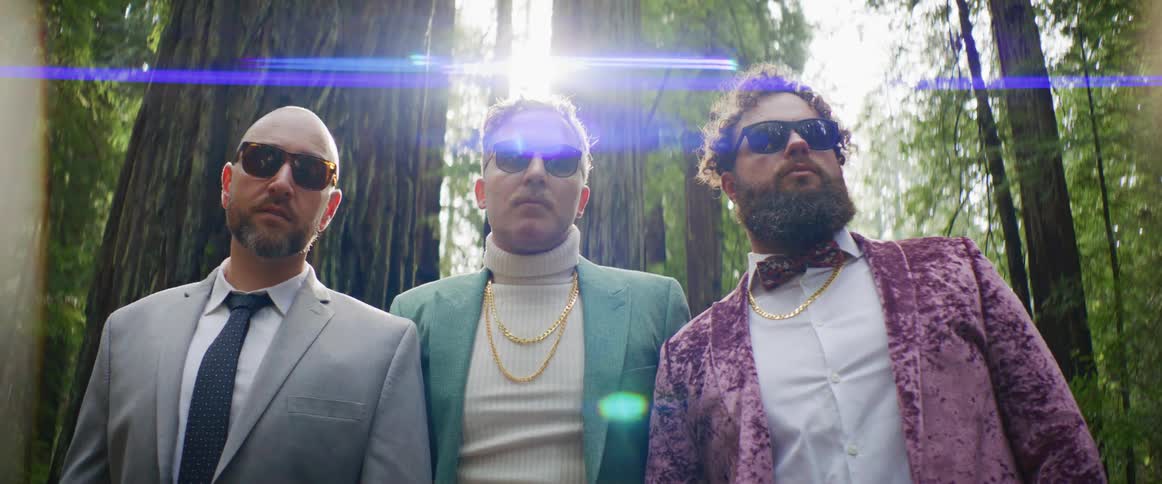 Three men pose together in front of the forest