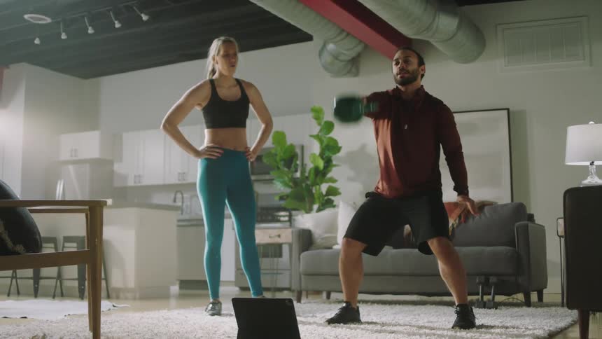 Two people are lifting weights indoors together