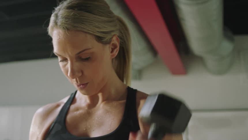 Blonde woman stands in home lifting hand weights and talking