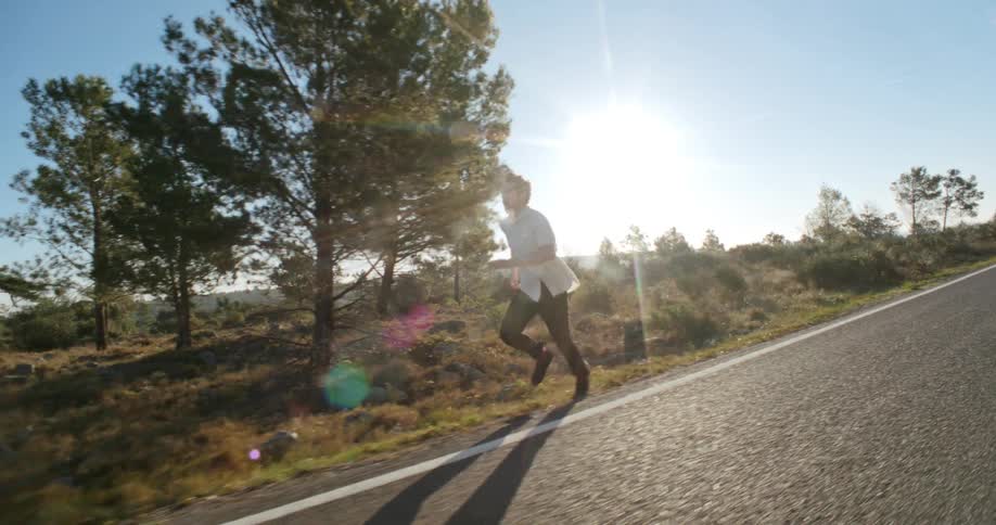 A man runs down the shoulder of a sloped highway
