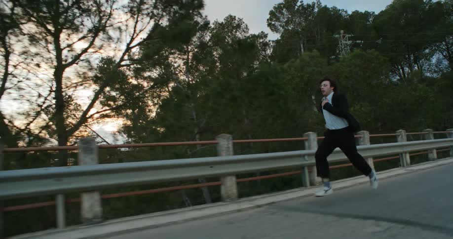 A man is jogging on a road outdoors at dusk