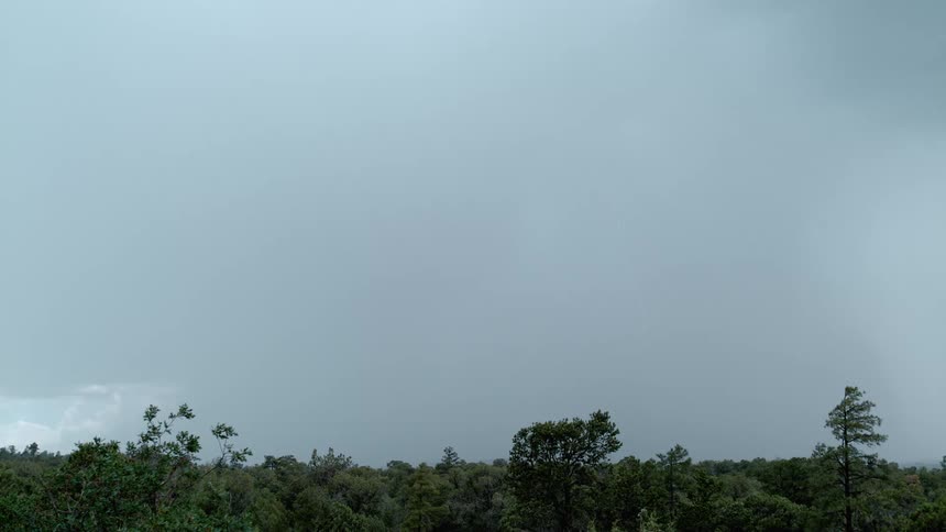 Lightning flashing and striking towards the ground from gray storm clouds