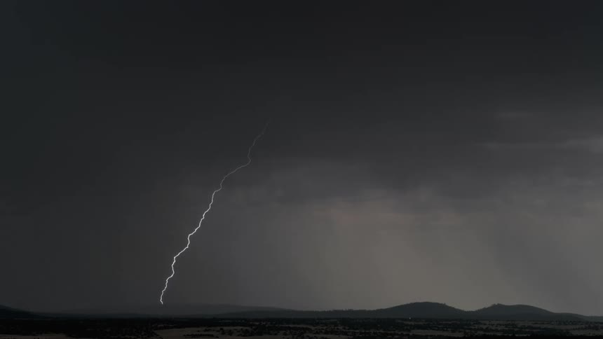 Lighting strikes over rolling hills