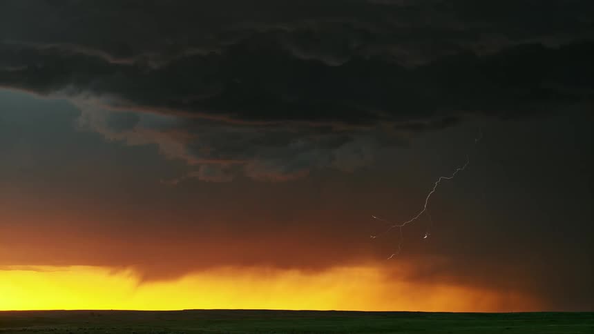 Dark gray storm clouds are gathering with lightning at sunset