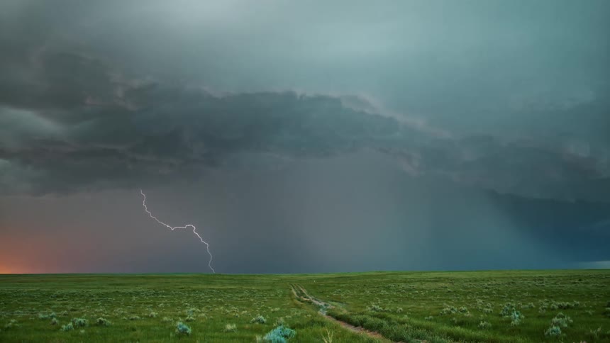 A thunderstorm is happening over the green landscape