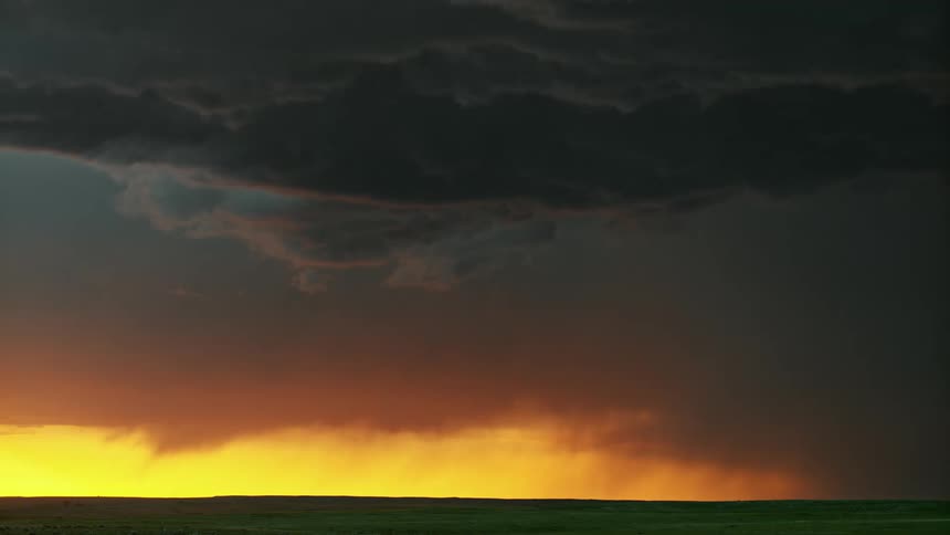 A flash of lightning comes out of dark clouds over a grassy field