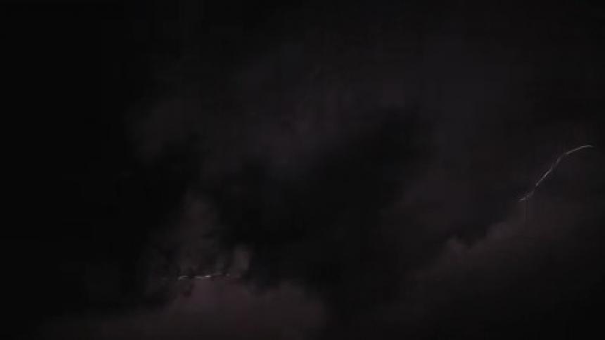 Flashes of lightning strike though dark dense clouds
