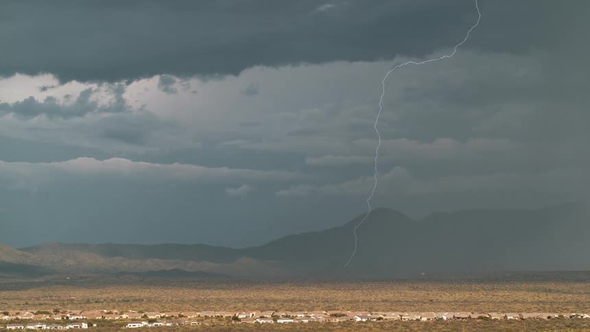 A storm is flashing lightning on the desert