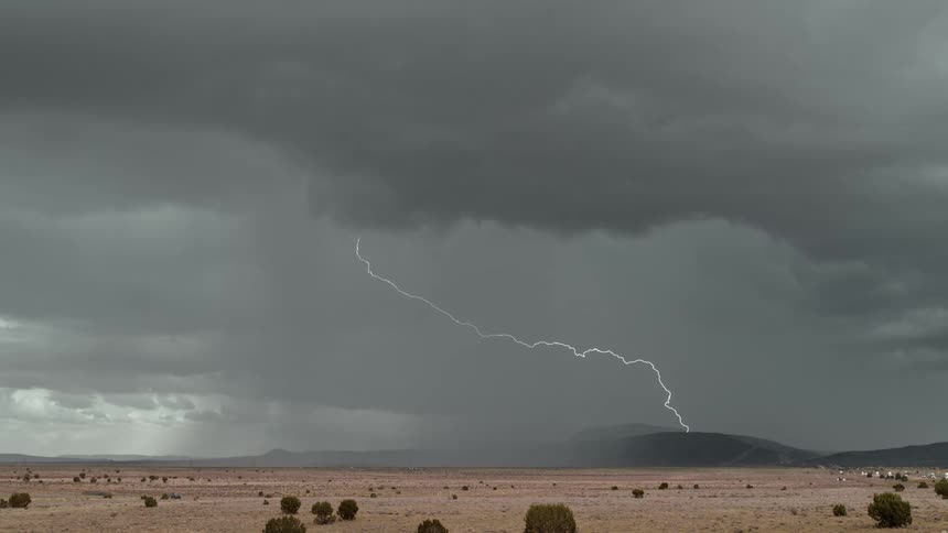 Lightning strikes through dense clouds over the desert
