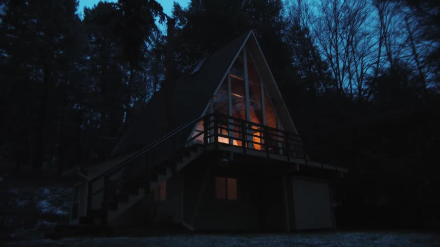 A house is displayed in the woods at night