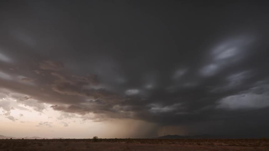 Dark storm clouds moves over a flat landscape as lightning flashes