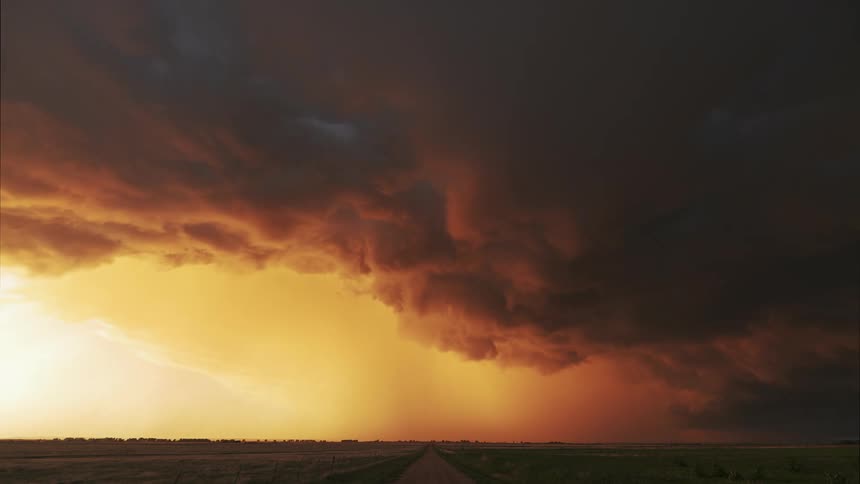 Storm clouds floating over a grassy plain at sunset