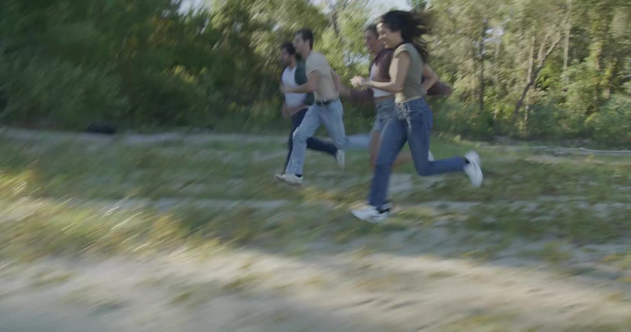 Young men and women run with one another near a forest
