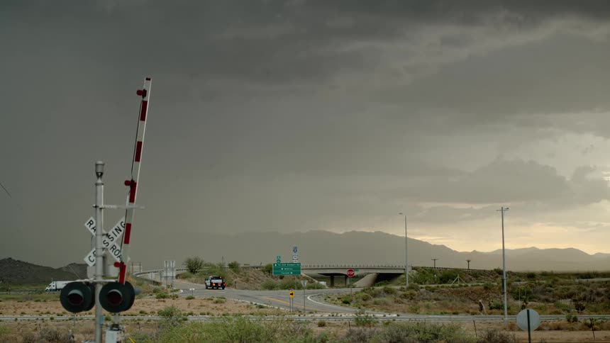 Cars are driving on a highway during a storm at dusk