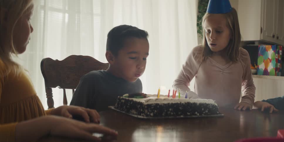 A boy blows out the candles on his birthday cake and everyone cheers