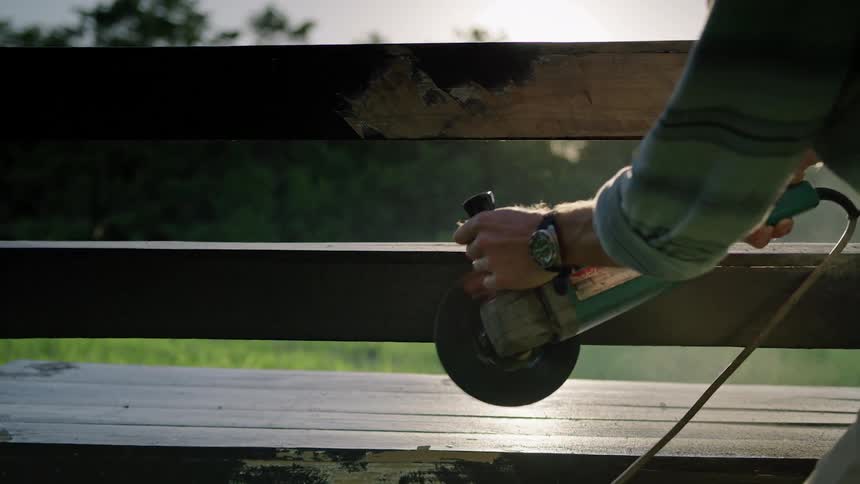 Person sands wooden bench with powered hand held sander