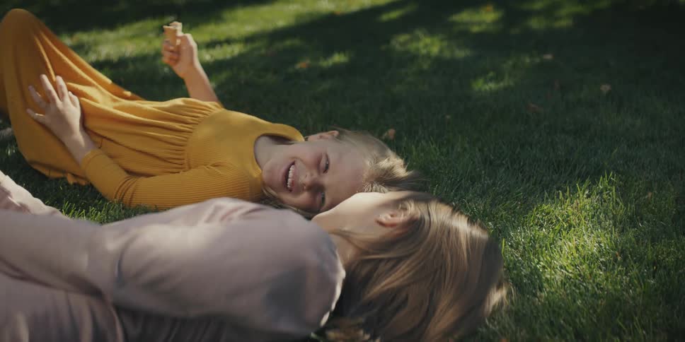 Two children laying in the grass talking