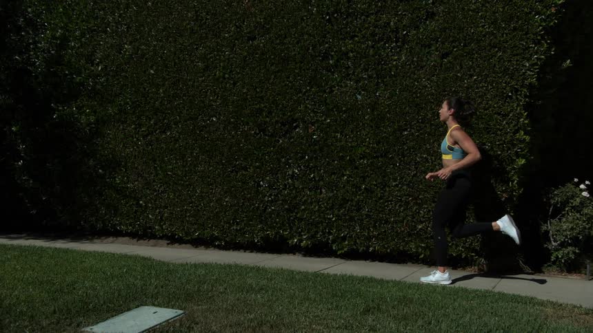 A woman is jogging on the sidewalk