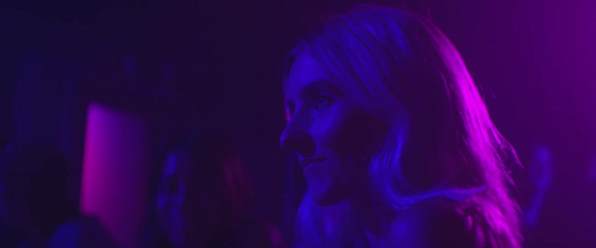 Blonde woman drinking under purple and blue lighting
