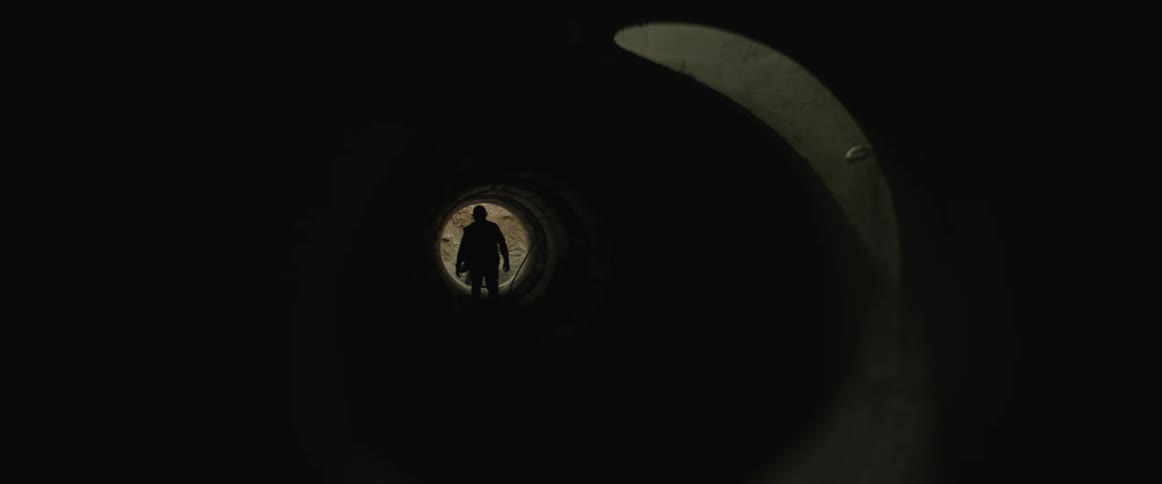 Silhouette of a construction worker walking out of a subterranean pipe to help a coworker shoveling dirt