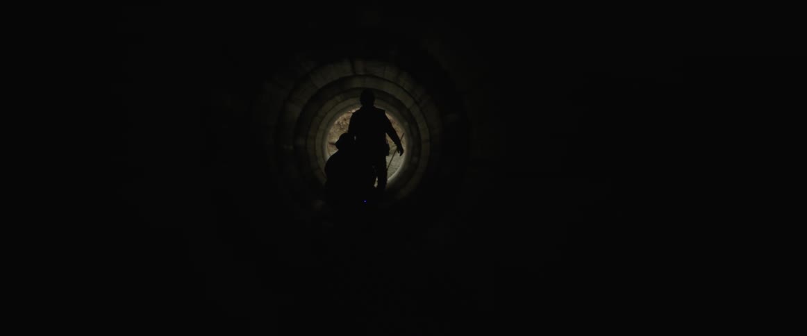 Two workers with a flashlight in a concrete tunnel